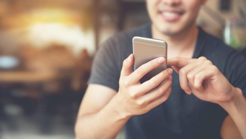 Happy male using smartphone at modern coffee shop, he chatting O